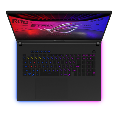 ภาพมุมมองจากด้านบน เห็นแล็ปท็อปเกมมิ่งที่หน้าจอเปิดอยู่และแสดงโลโก้ ROG STRIX พร้อมพื้นหลังสีแดงและน้ำเงิน คีย์บอร์ดมีไฟ RGB สีสันหลากหลาย ปุ่ม WASD และปุ่มตัวเลขบางปุ่มมีสีแตกต่างกันอย่างชัดเจน ด้านล่างของแล็ปท็อปมีแสงไฟ RGB ล้อมรอบเป็นสีฟ้าและชมพู ทัชแพดขนาดใหญ่ อยู่ตรงกลางด้านล่างของคีย์บอร์ด